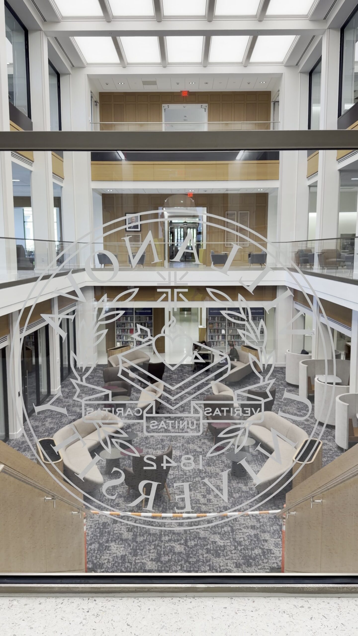 Acid-etched collegiate seal glass panel with the library atrium seating behind it