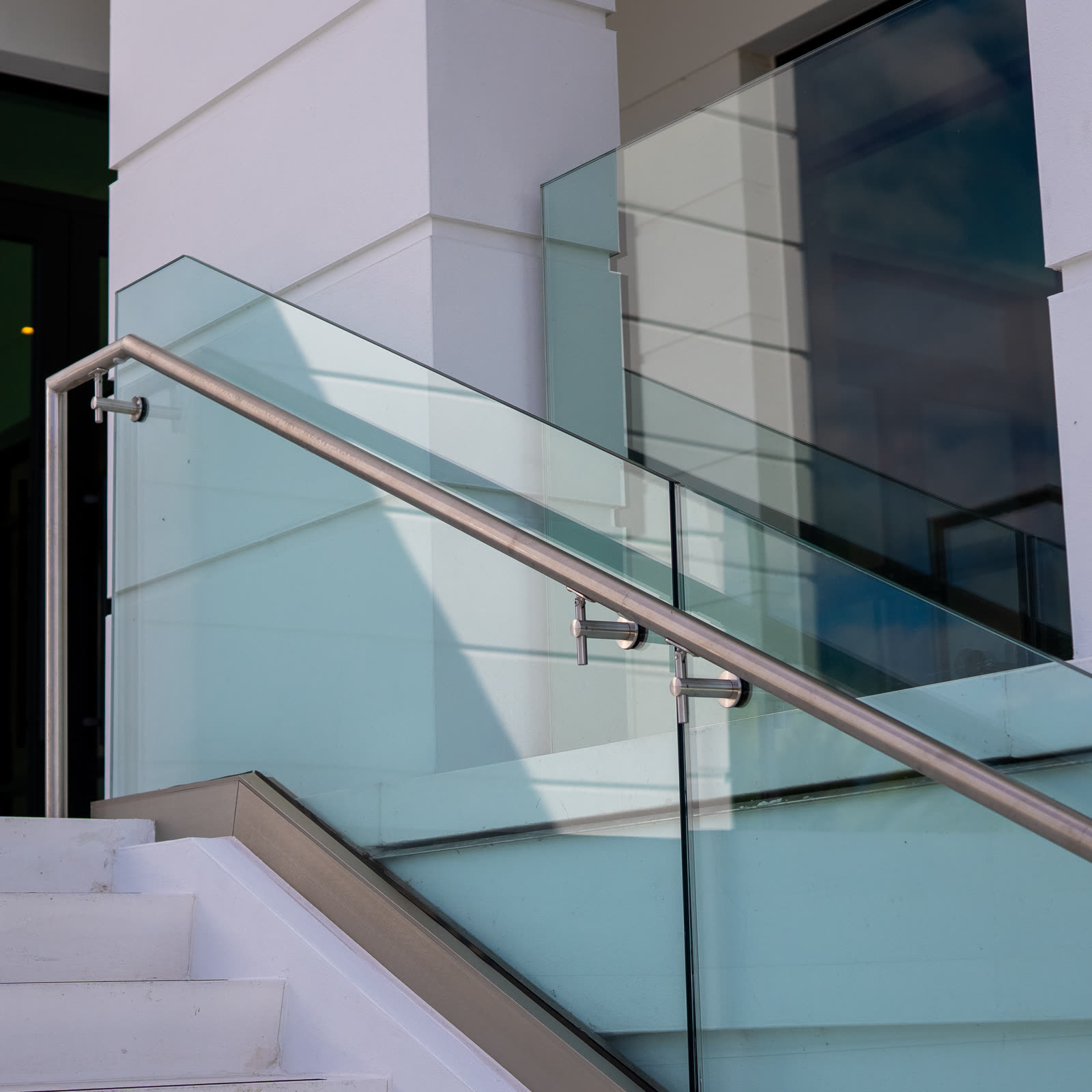 Stainless steel handrail and laminated glass guardrail on an exterior clubhouse stair