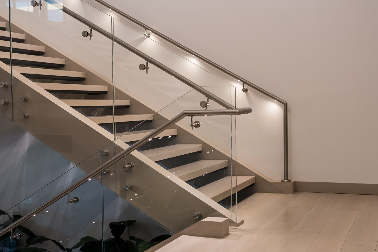 Interior stair with standoff-mounted glass panels and a continuous handrail